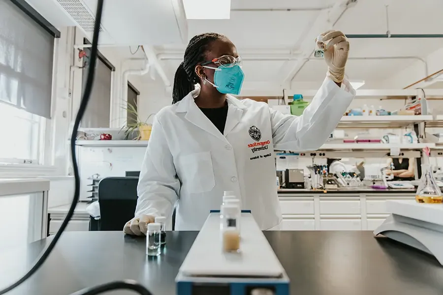 scientist in lab coat holding up a vial